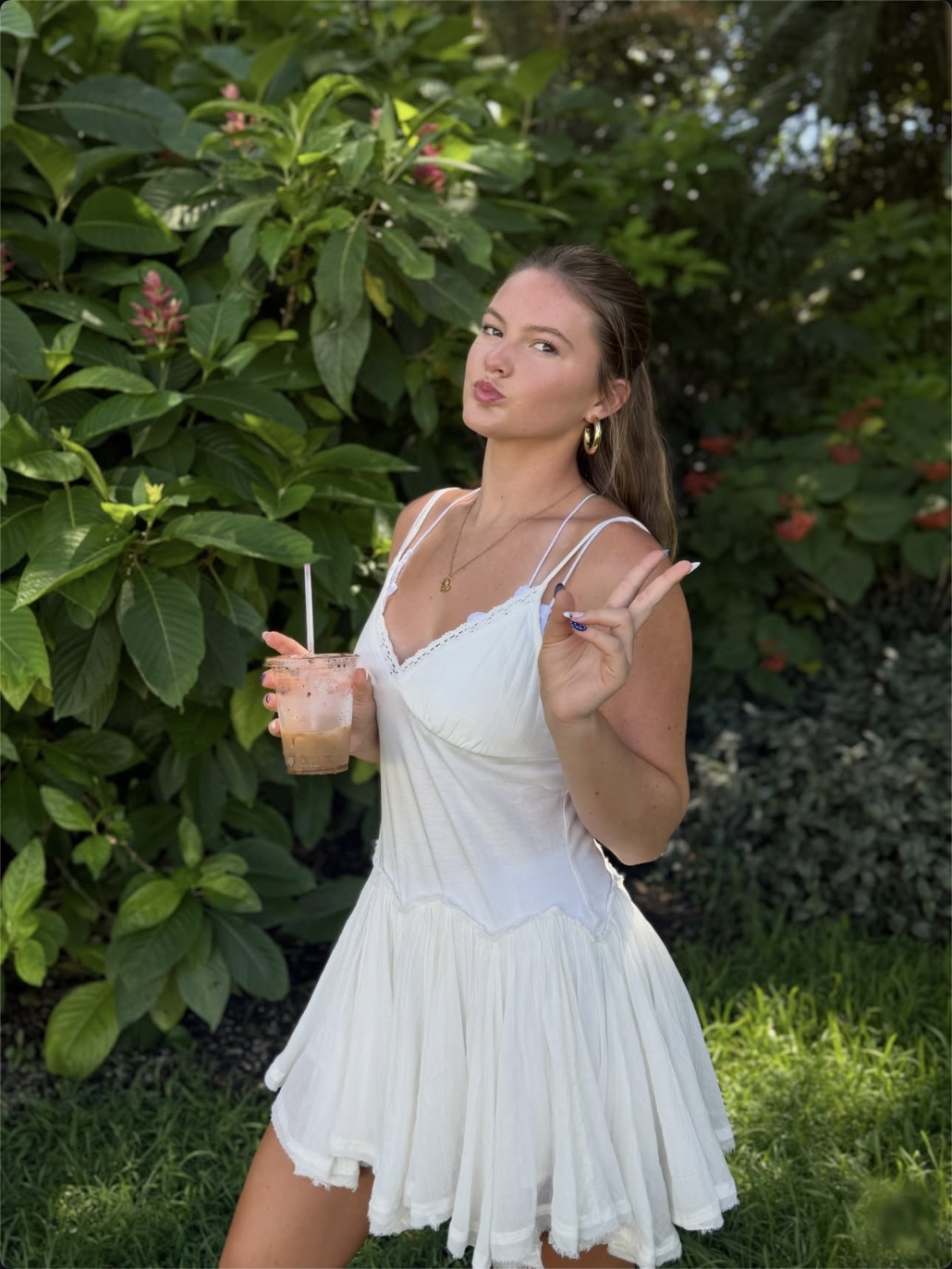 Cailyn Campbell in a white dress holding an iced coffee